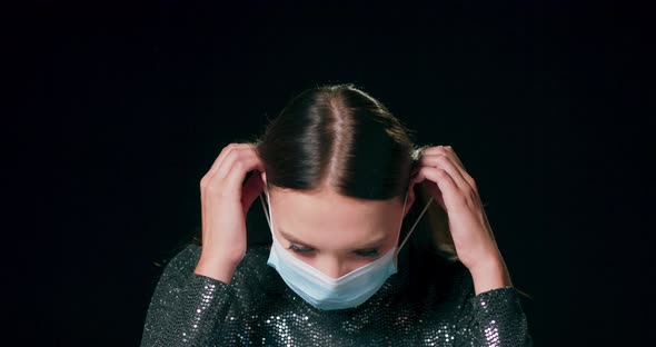 Closeup of a Teenage Caucasian Girl Wear Brocade Dress Putting on a Protective Medical Face Mask alt