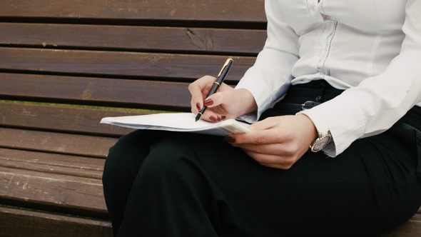 Closeup Of Business Woman Writing With Pen In A Notebook