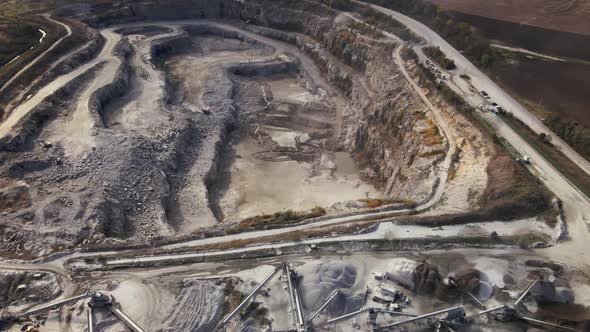 Aerial view of Slope operating granite quarry with mining equipment on ledges alt