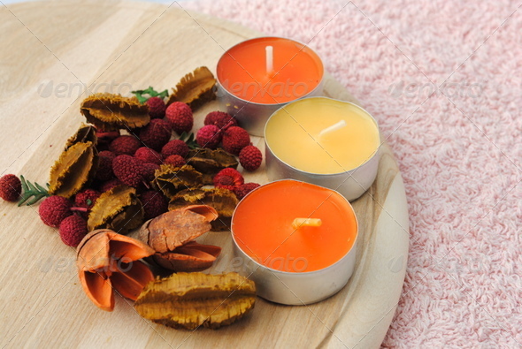 three candles with dried flowers in wooden dish
