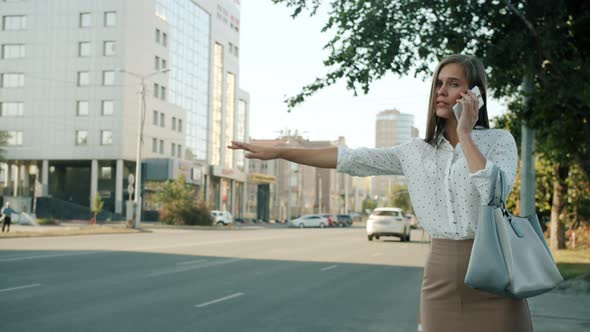 Slow Motion of Nervous Girl Waving Hand Waiting for Taxi Talking on Mobile Phone in Metropolis alt