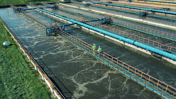 Two Wastewater Operators Walking Along the Pipes at a Sewage Cleaning Facility alt