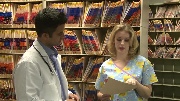 Doctor And Nurse Discuss Patient's Chart (1 Of 3)