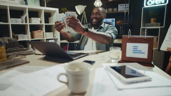 Cheerful African Businessman Counting Money in Late Night Office in Slow Motion. alt