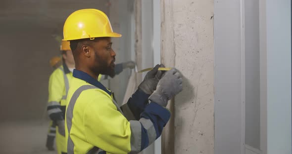 Workmen Using Tape Measuring Walls for Home Renovation alt