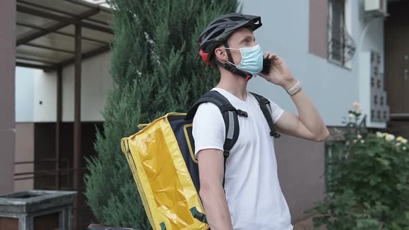The Delivery Man Talks with the Customer of Food by Mobile Phone. Coronavirus, COVID-19 alt