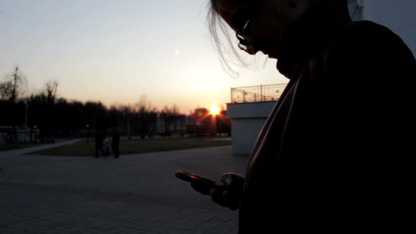 Woman Using Smartphone on Sunset
