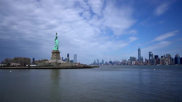 Statue of liberty island with New York City skyline in background across water alt