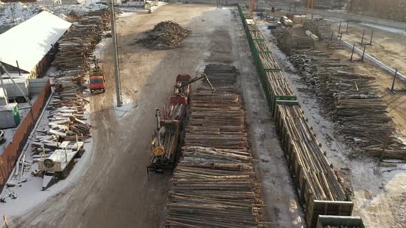 Aerial View of Logging Train at Sawmill Hauls Stacked Wooden Logs and Tree Trunks. Train at the alt