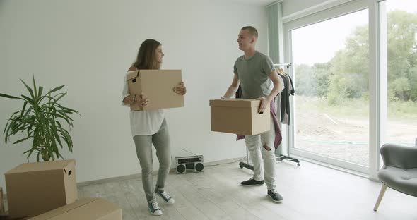 Young Couple Carrying Boxes in New Apartment