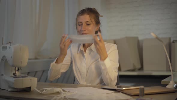 Portrait of Smiling Woman Sewing Covid Face Mask and Putting It On. Happy Confident Caucasian alt