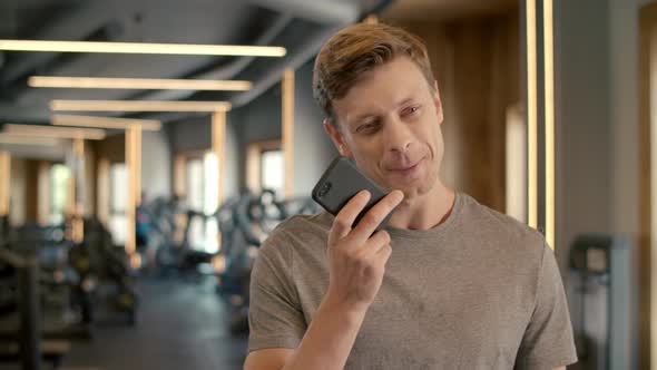 Cheerful Bodybuilder Speaking on Phone at Gym. Sportsman Standing in Sport Club alt