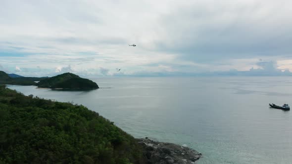 Helicopter flying back to barge to get next load of supplies for tropical island alt