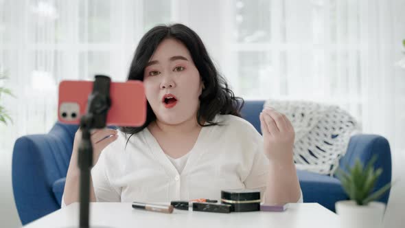 plus size Asian woman bloggers sitting are online to review cosmetic products via social media