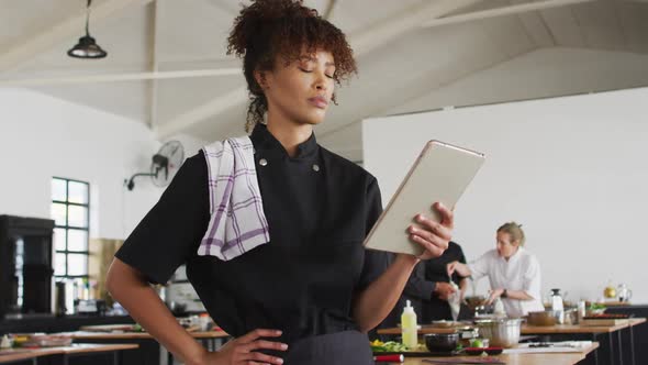 Mixed race female chef using digital tablet alt
