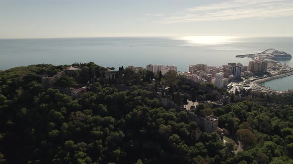 Moorish castle and Malaga port in background. Aerial backward ascending
