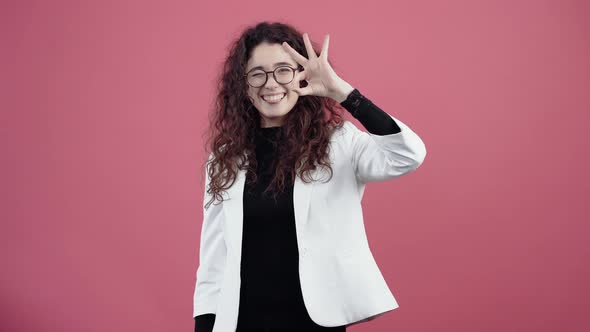 Happy Young Woman with Curly Hair Looks Good with Her Hand Smiling and Sticking Her Tongue Out alt