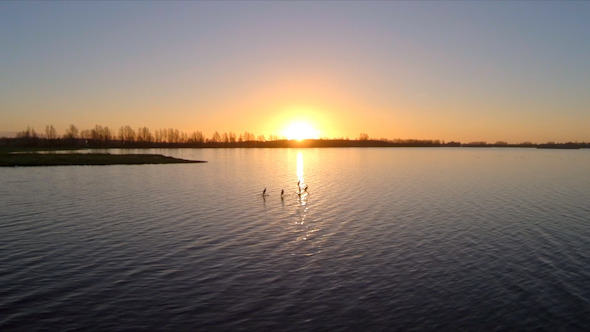 Flying Towards the Sunset Over a Lake alt