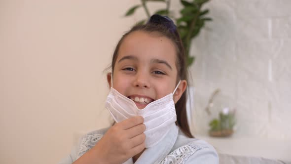 Little Girl Takes Off Her Protective Medical Mask and Smiles alt