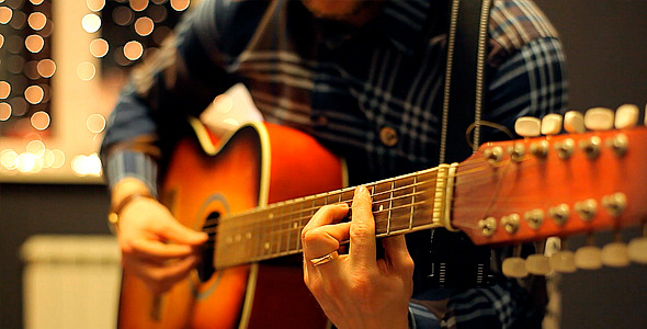 Man Playing an Acoustic Guitar on a Beautiful Back