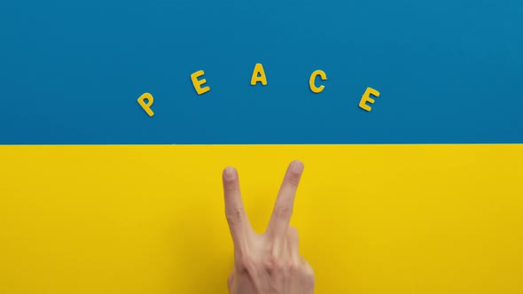 Victory and Peace with Hand Making Symbol on the Flag of Ukraine alt
