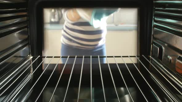Woman Putting Dish Of Vegetables Into Oven To Roast