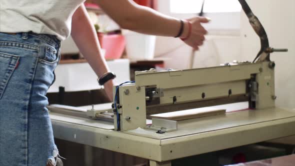 Woman Cutting Sheets of Cardboard in Manual Paper Cutter Machine in Typography