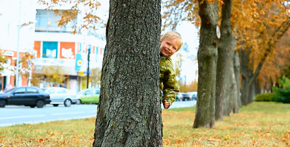 Child Hiding Behind Tree in Park