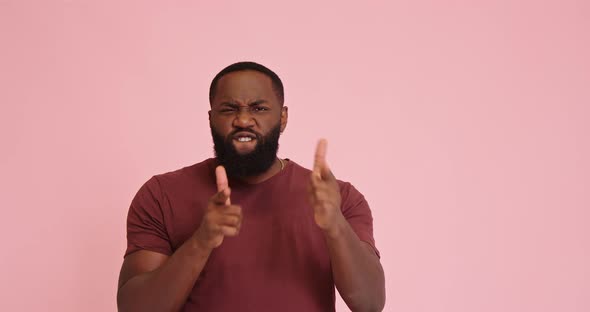 Young African American Man Pointing with Finger Pistols Isolated on Pink Background alt
