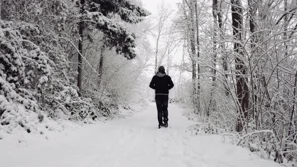 Anonymous man walking on snowy path alt