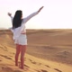 Back View Young Beautiful Caucasian Woman Standing in Sandy Desert and Raises Her Hands Up - VideoHive Item for Sale