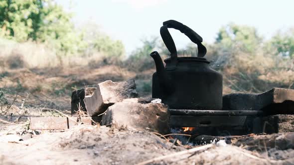 Tourist Kettle Standing on a SelfMade Campfire Stove in Tourist Camp in Nature alt