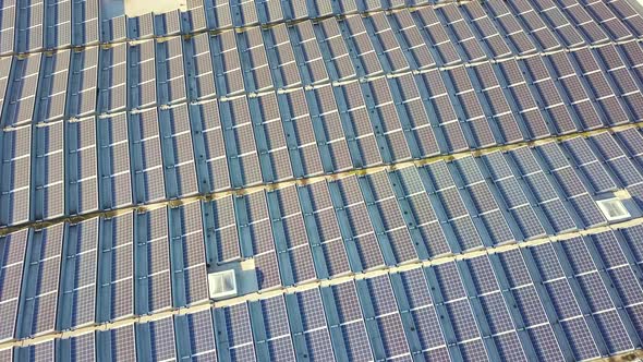 Aerial view of many photo voltaic solar panels mounted of industrial building roof. alt