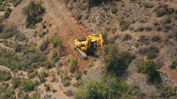 Yellow Excavator Dig Stony Ground in Wild Mountains
