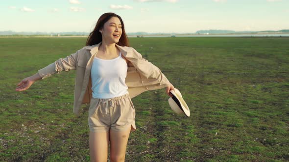 cheerful woman walking across the green field with sunlight