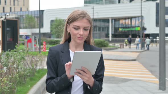 Attractive Young Businesswoman Using Tablet While Walking on the Street alt