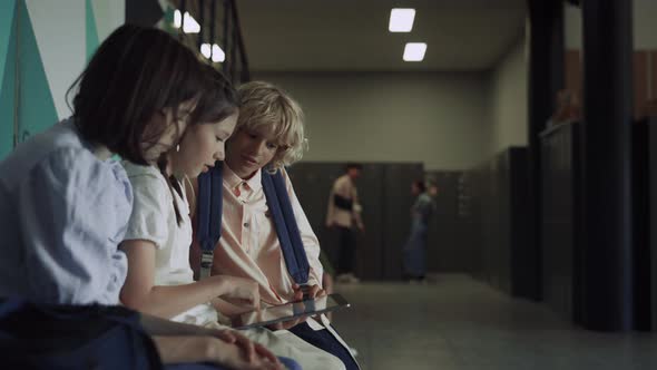 Three Focused Students Sitting with Tablet in School Hall alt