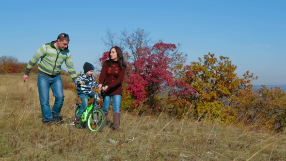 Happy Young Family With a Child Walking In Autumn