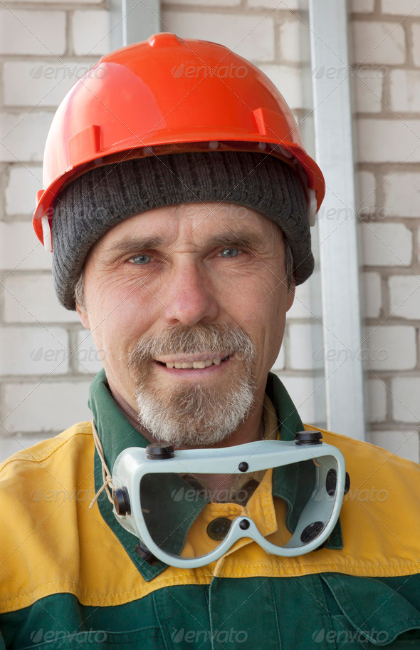 An elderly worker with spectacles and a protective helmet