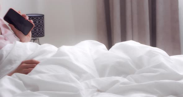 Woman Listens to Music Through Headphones Sings and Dances Lying in Bed alt