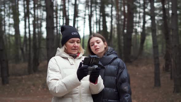 Caucasian Woman with Adult Daughter Flying Aerial Drone in Autumn Forest alt