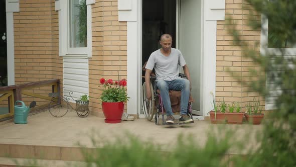 Paralyzed African American Man Riding Wheelchair on Backyard Porch Outdoors alt