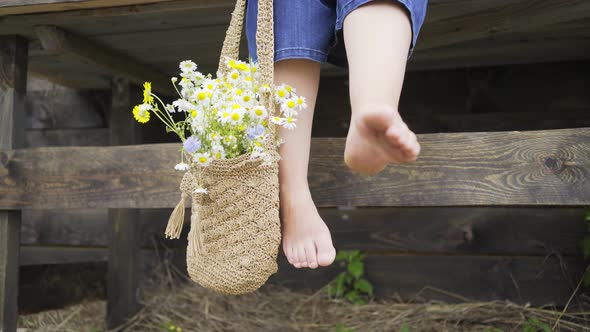 Barefoot Woman with Bag Full of Windflowers Sits on Table