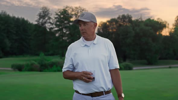 Relaxed Senior Looking Camera on Green Nature Golf Course alt