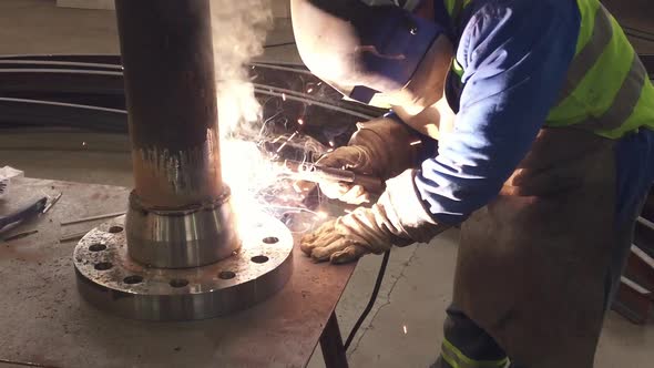 Worker welding a metal peace in an industrial space. Slow motion. alt