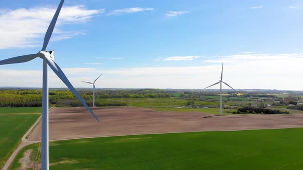 Drone flying sideways getting nice view of three spinning windmills alt