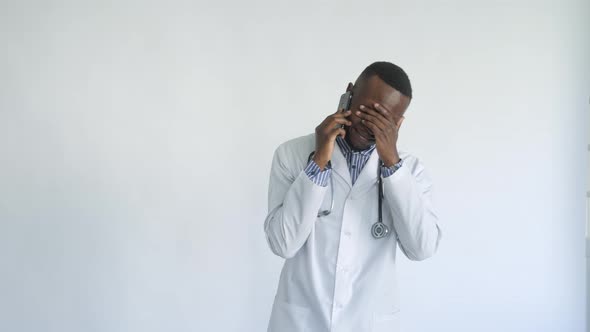 Blackskinned Young Medic Smiling Standing on a White Background Talking on the Phone alt