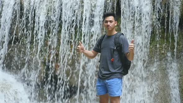 Man Standing In Front Of  Waterfall With Thumps Up alt