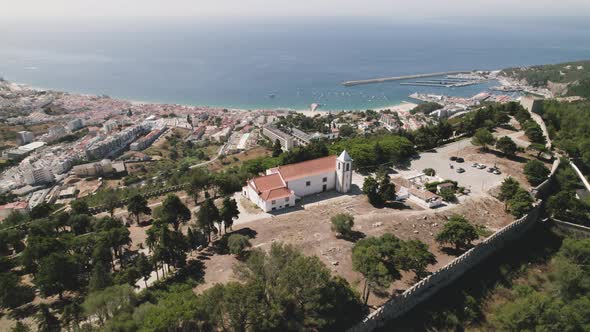 Church of Nossa Senhora de Castelo in Sesimbra Portugal, aerial orbital shot 4k alt