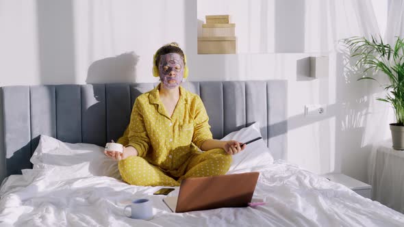 Woman in Funny Facial Masks Meditate in Bed